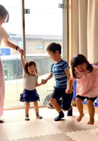 AES英会話の幼児クラスで親子が手をつないで遊びながら英語にふれる様子。
