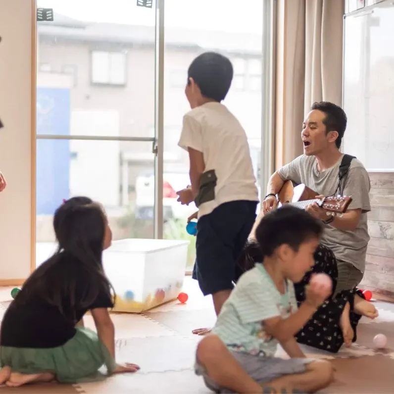 垂井町のAES英会話教室での音楽アクティビティ。先生がギターを弾きながら、子どもたちが自由に英語で遊ぶ楽しい雰囲気のレッスンです。